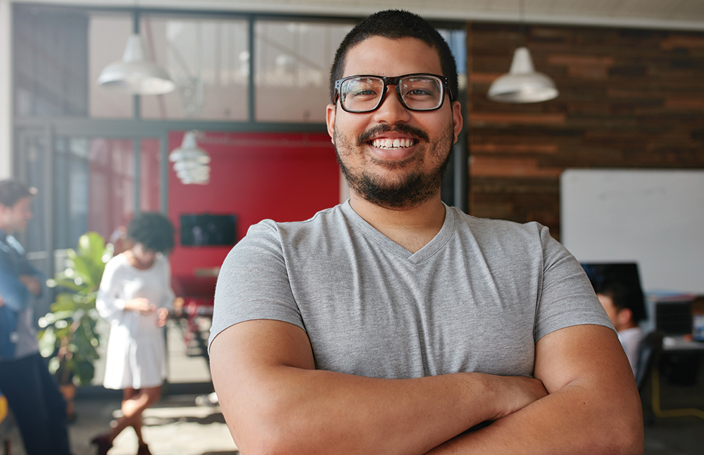 Smiling man standing in an office with his arms folded