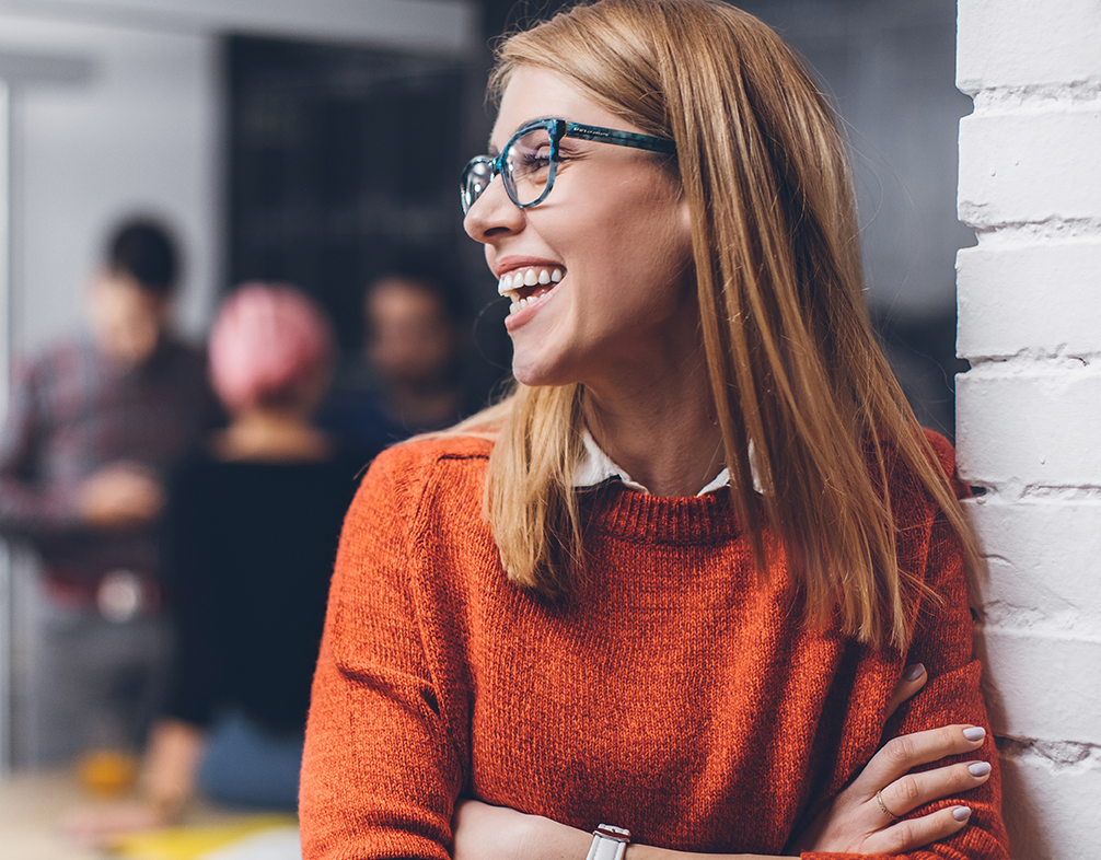 Smiling woman leaning against a wall and smiling off to the left Smiling woman leaning against a wall and smiling off to the left