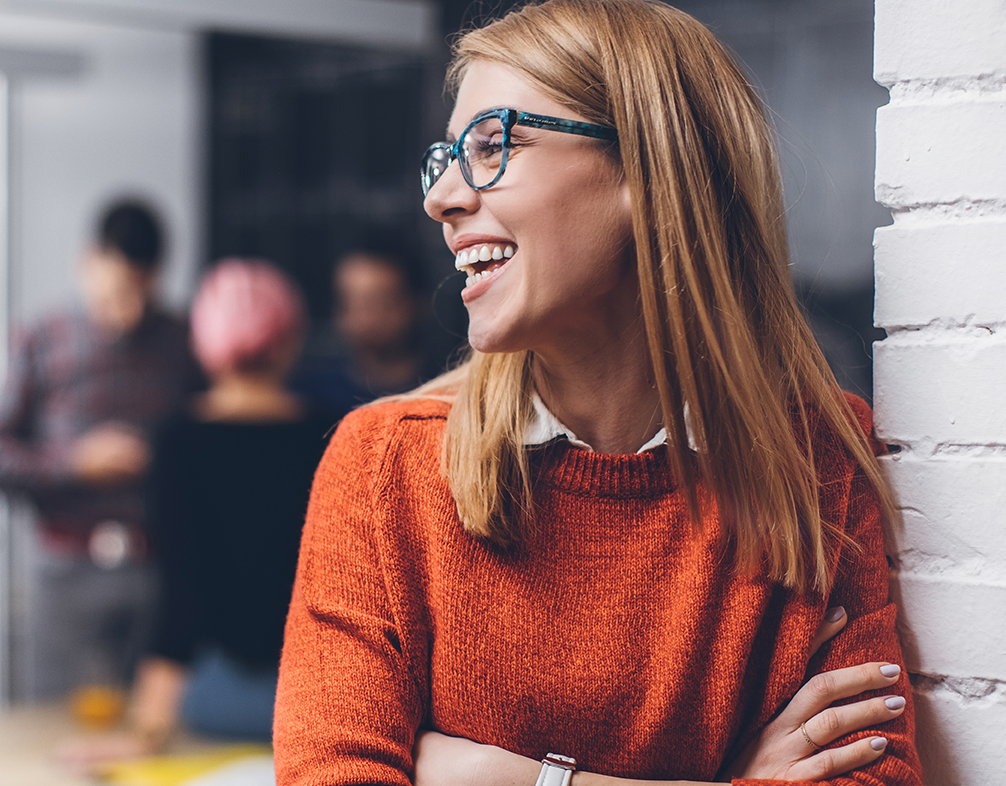 Smiling woman leaning against a wall and smiling off to the left