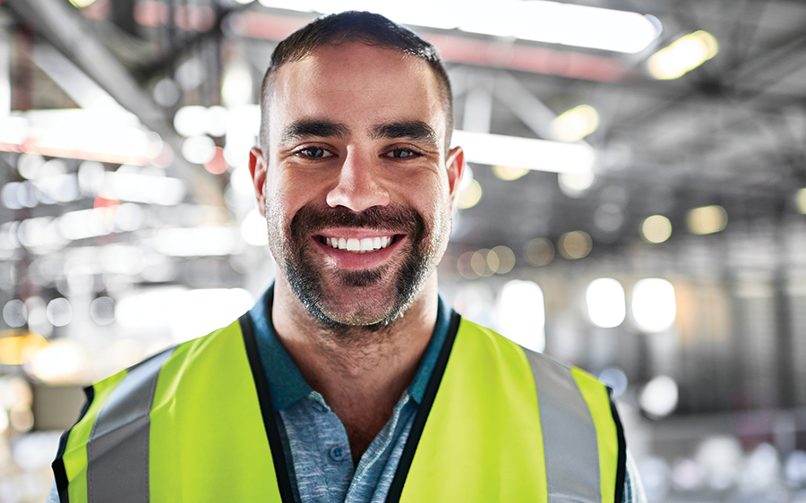 Young male factory worker smiling at camera