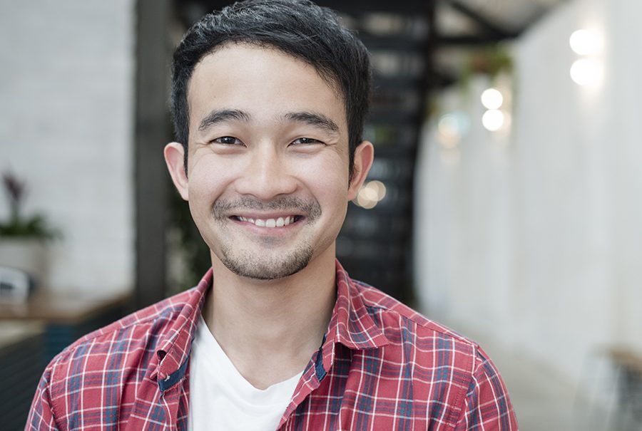 Casual young Asian businessman smiling towards camera Casual young Asian businessman smiling towards camera