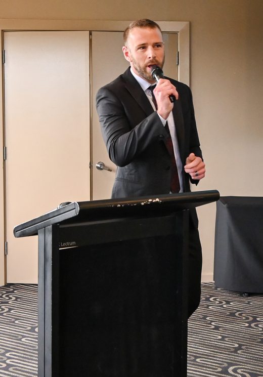 Shaun speaks into a microphone in a dapper suit