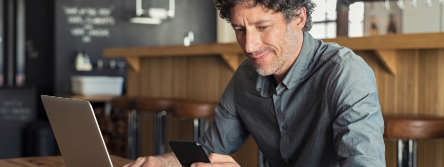 Man looking at his phone and laptop computer